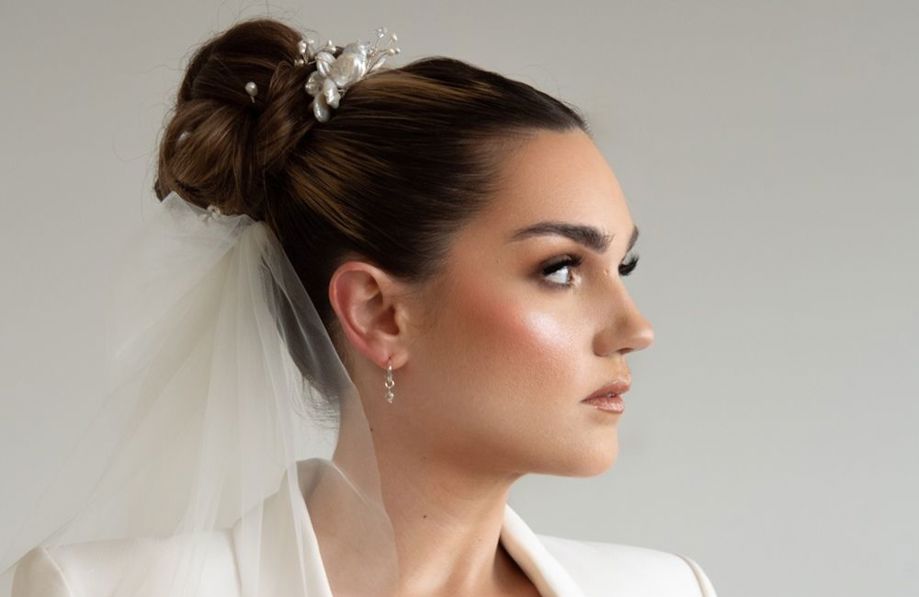 Bride with sleek updo looking to the right with veil on and white suit jacket